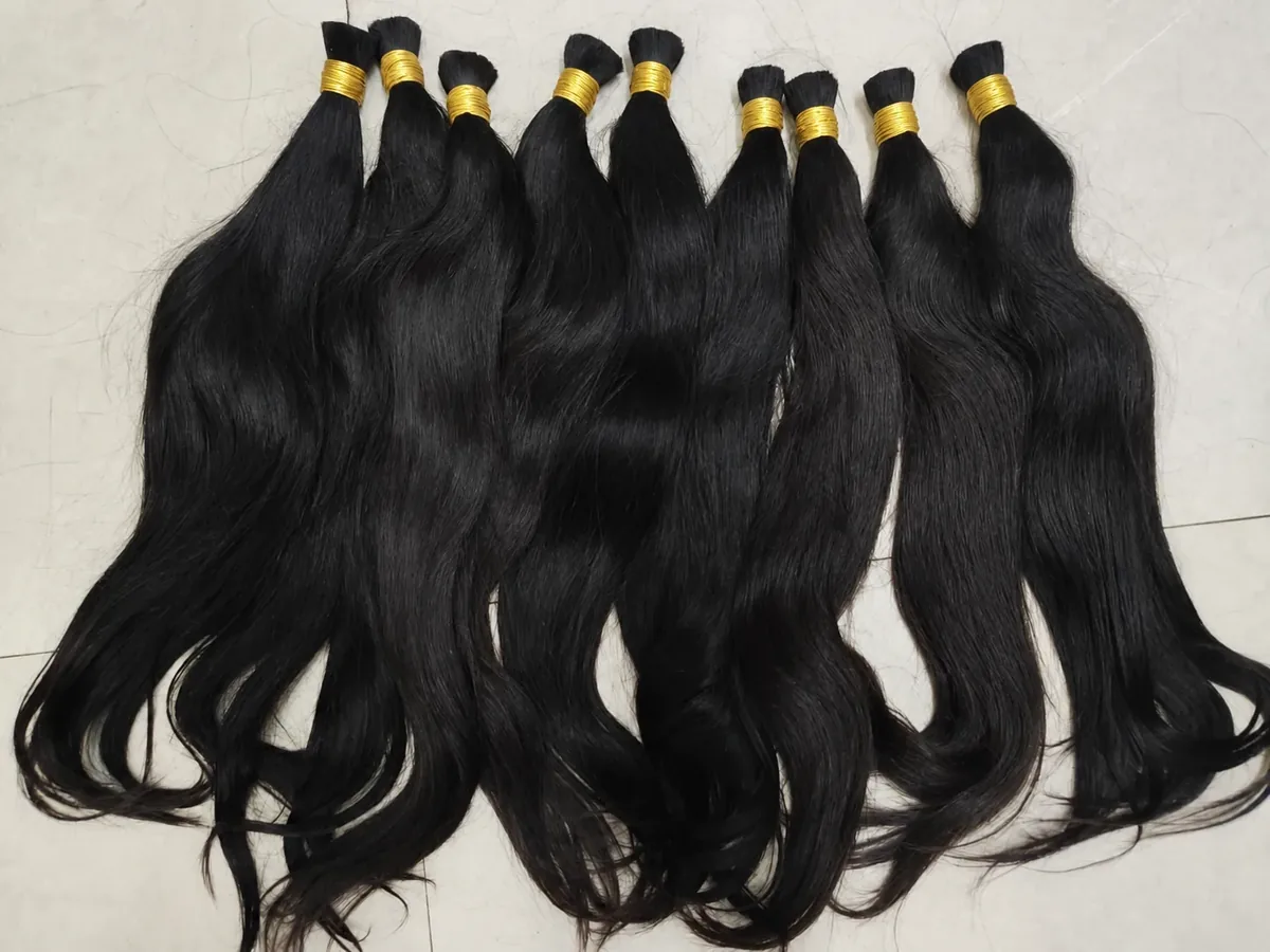 Các bó tóc bulk Việt Nam màu đen tự nhiên buộc dây vàng xếp trên sàn sáng màu